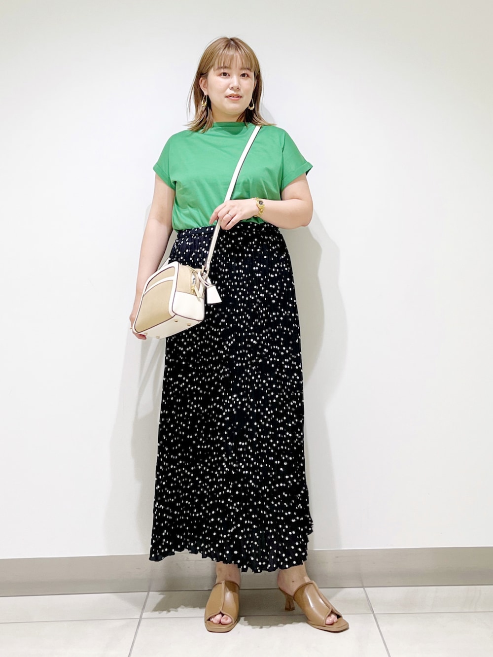 グリーン系のTシャツ/カットソー、ブラック系のスカート、ベージュ系のサンダルを着用したレディースの夏コーディネートの2枚目の写真