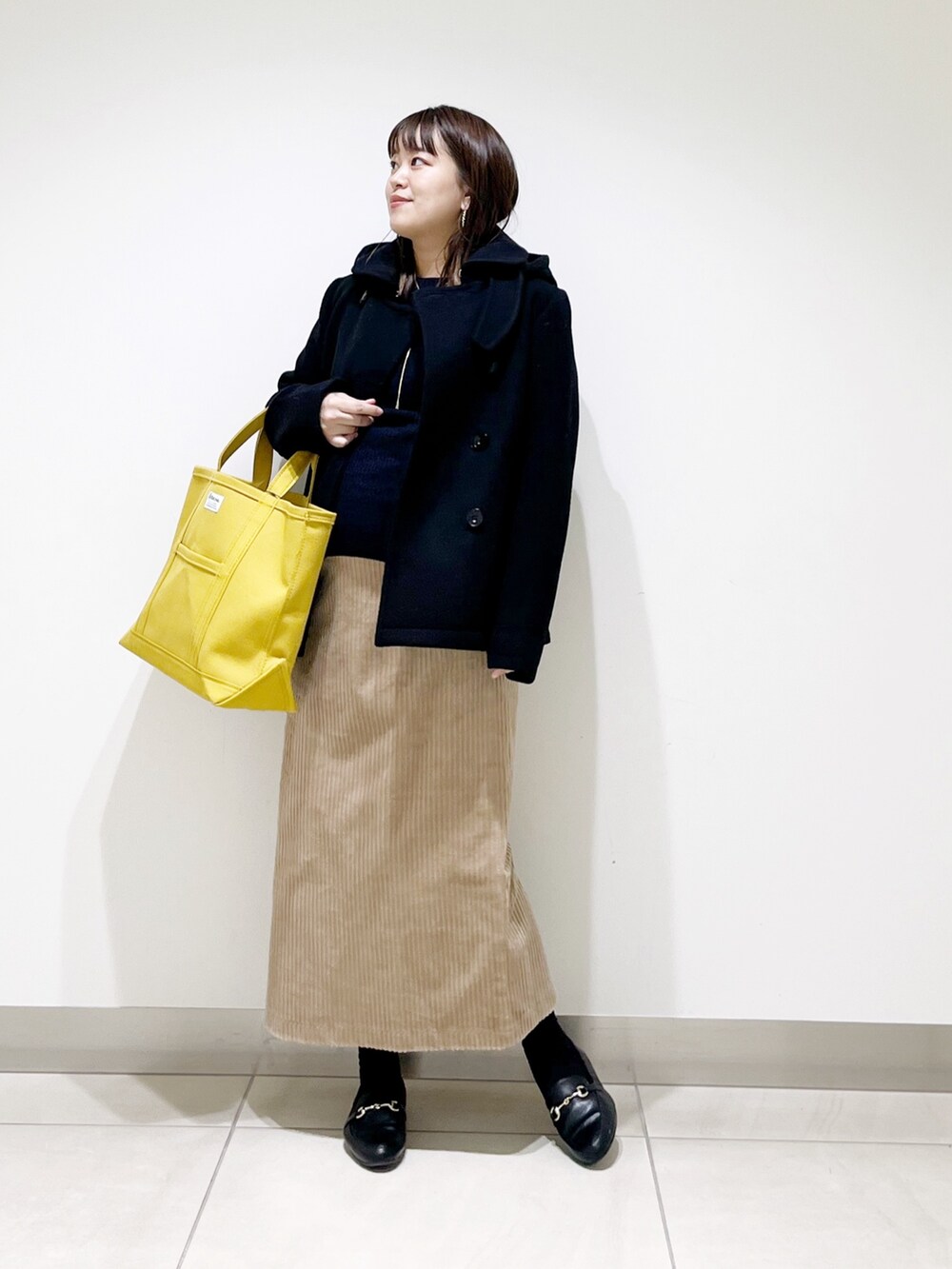 ブラック系のピーコート、ブルー系のニット/セーター、ブラック系のローファーを着用したレディースの冬コーディネートの10枚目の写真