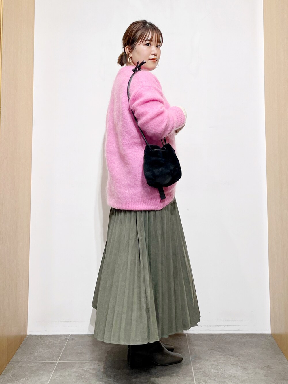 ピンク系のニット/セーター、グリーン系のスカート、グレー系のブーツを着用したレディースの秋コーディネートの5枚目の写真