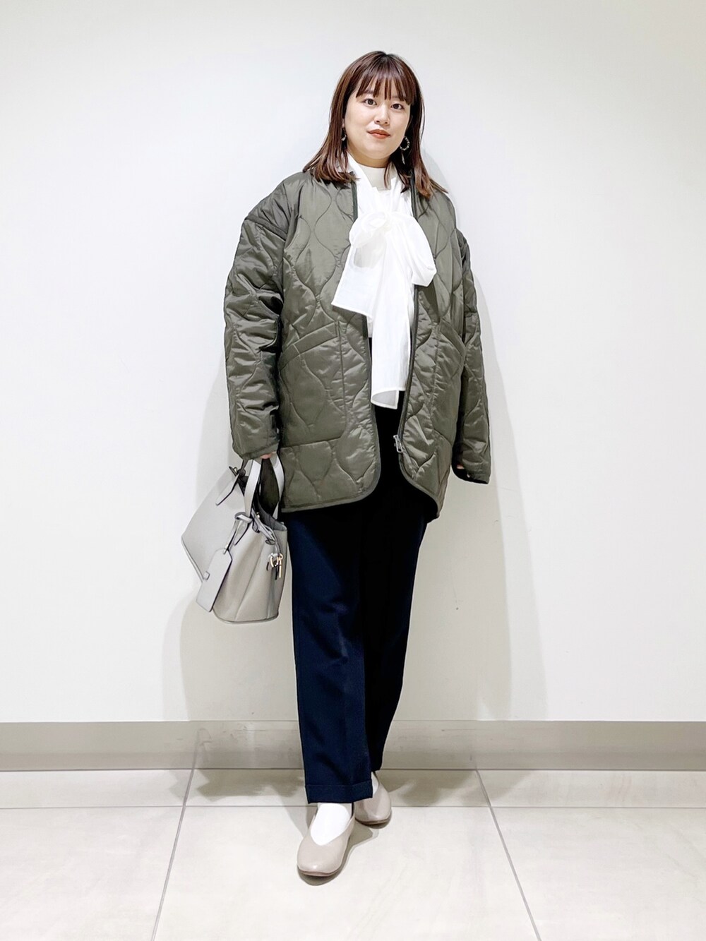 グリーン系のダウンジャケット/コート、ブルー系のパンツ、グレー系のトートバッグを着用したレディースの秋コーディネートの9枚目の写真