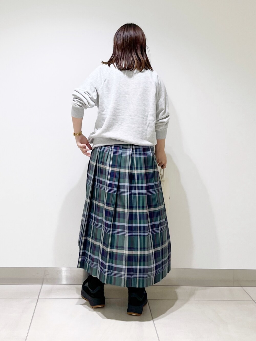 グリーン系のスカート、グレー系のスウェット、ホワイト系のショルダーバッグを着用したレディースの冬コーディネートの3枚目の写真