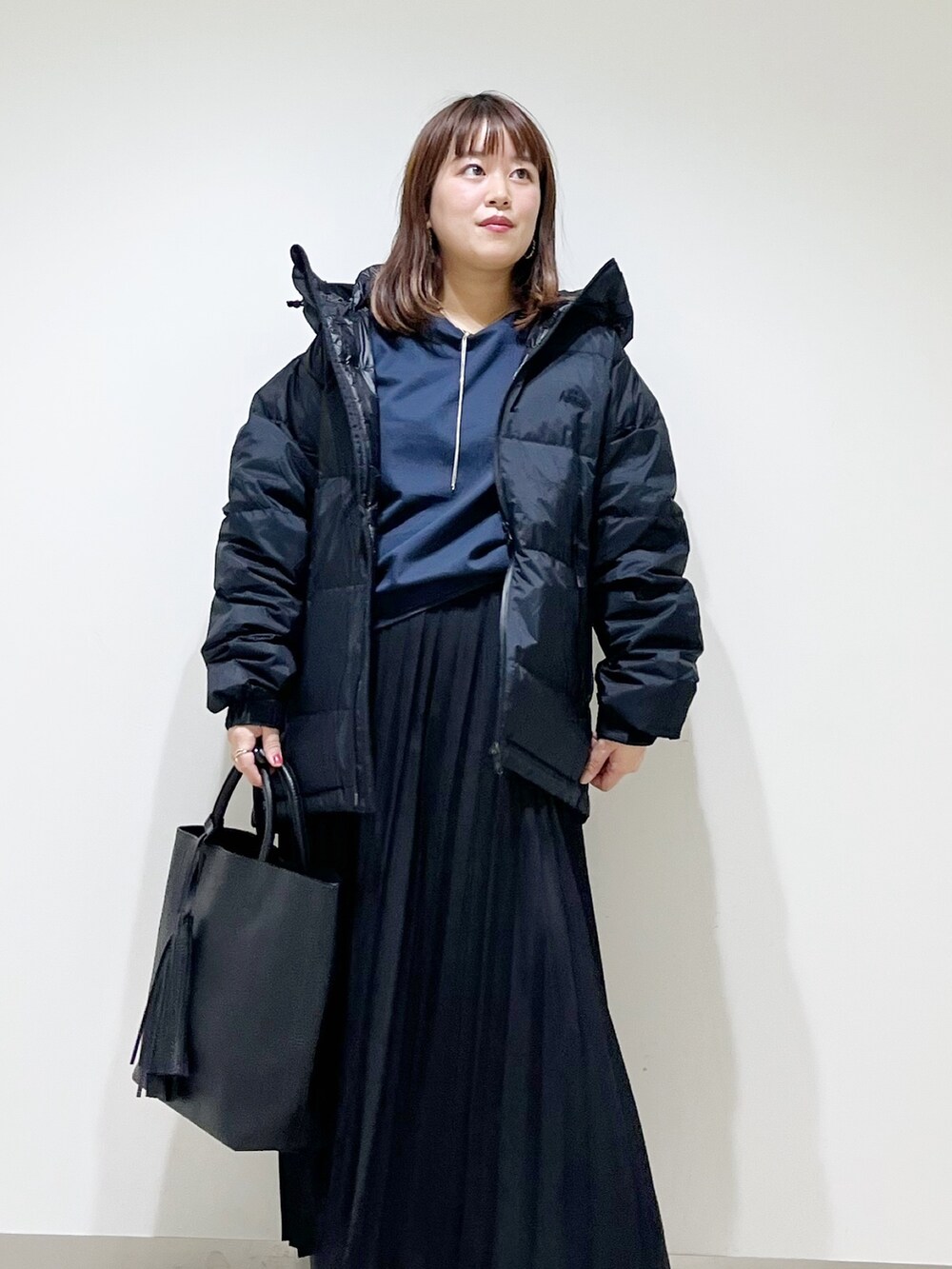 ブラック系のダウンジャケット/コート、ブルー系のTシャツ/カットソー、ブラック系のスカートを着用したレディースの秋コーディネートの4枚目の写真