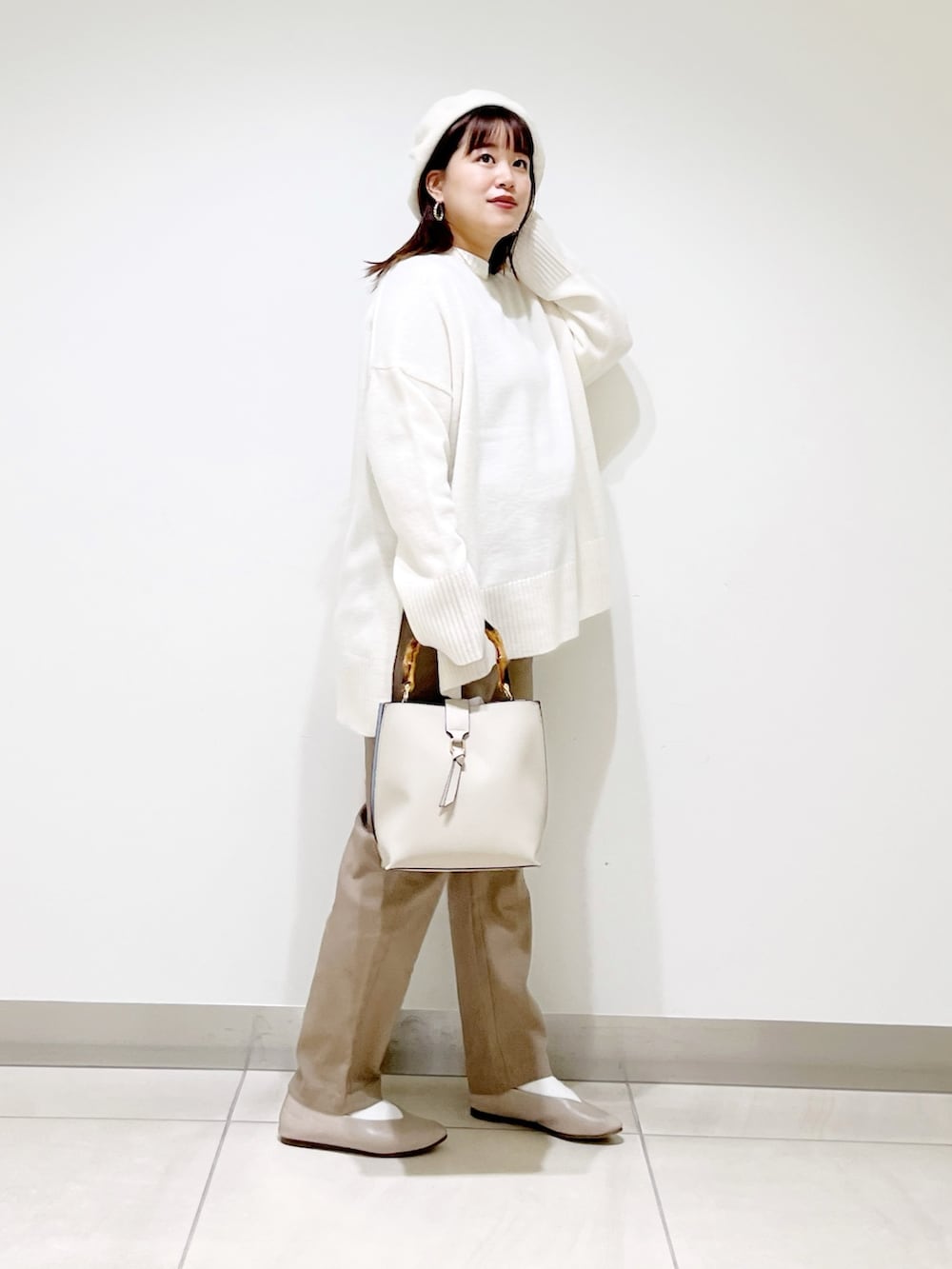 ホワイト系のニット/セーター、ホワイト系のハンドバッグ、ベージュ系のその他パンツを着用したレディースの冬コーディネートの10枚目の写真