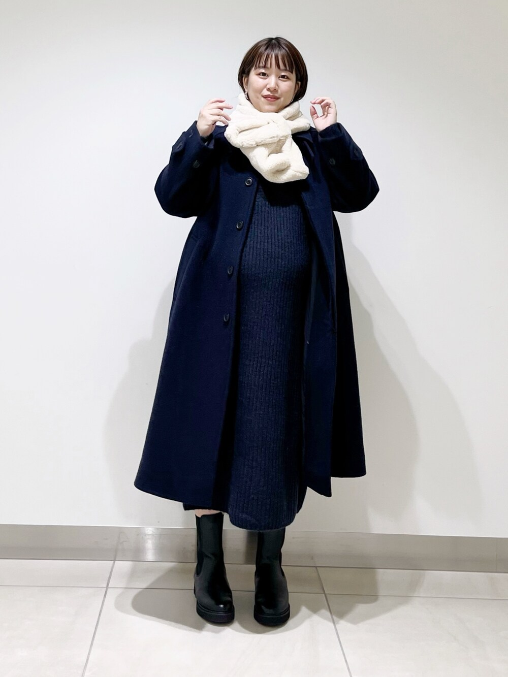 ブルー系のステンカラーコート、ブルー系のワンピース、ブラック系のブーツを着用したレディースの冬コーディネートの10枚目の写真