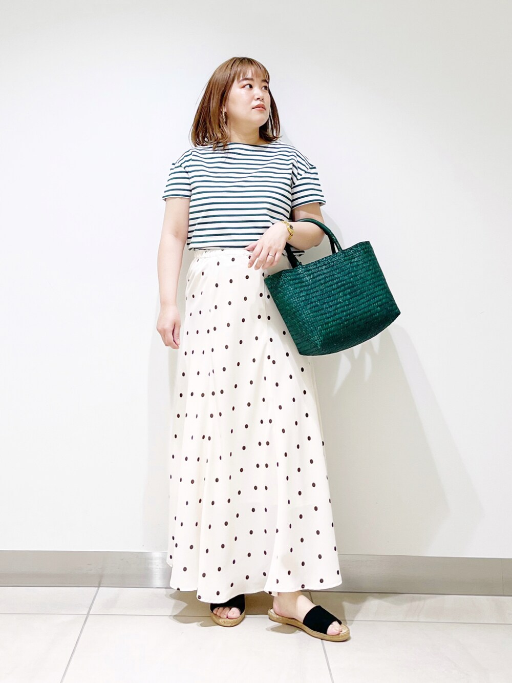 ホワイト系のスカート、グリーン系のかごバッグ、グリーン系のTシャツ/カットソーを着用したレディースの春コーディネートの5枚目の写真