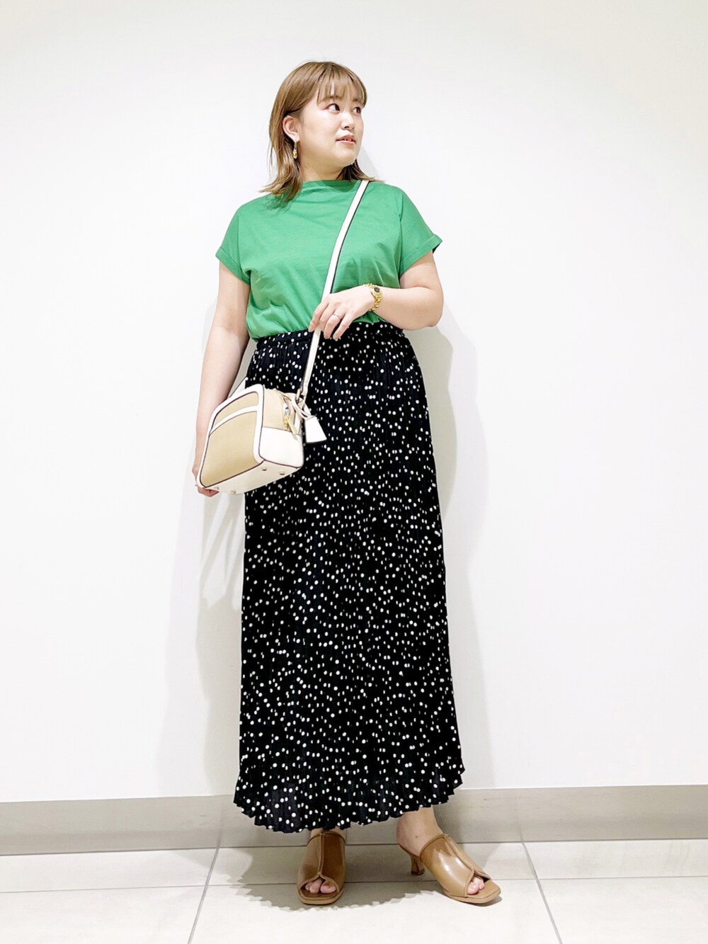 グリーン系のTシャツ/カットソー、ブラック系のスカート、ベージュ系のサンダルを着用したレディースの夏コーディネートの4枚目の写真