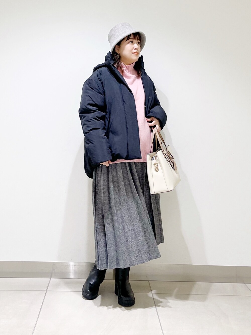 ブラック系のダウンジャケット/コート、ピンク系のニット/セーター、ブルー系のスカートを着用したレディースの冬コーディネートの6枚目の写真