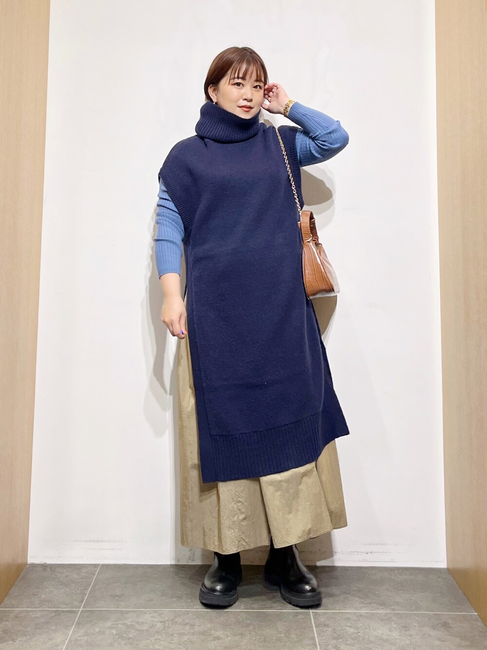 ブルー系のワンピース、ブラック系のブーツ、ベージュ系のスカートを着用したレディースの秋コーディネートの4枚目の写真