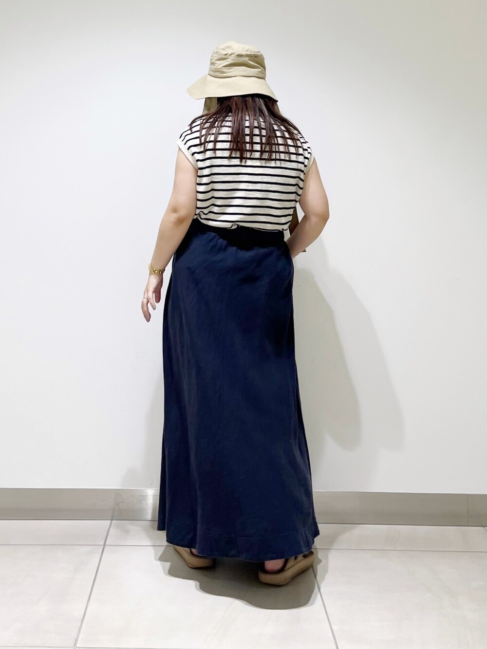 ベージュ系のTシャツ/カットソー、ブルー系のスカート、ベージュ系のサンダルを着用したレディースの夏コーディネートの8枚目の写真