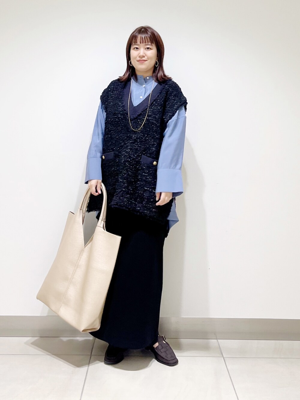 ブルー系のシャツ/ブラウス、ブラック系のスカート、ゴールド系のトートバッグを着用したレディースの秋コーディネートの2枚目の写真