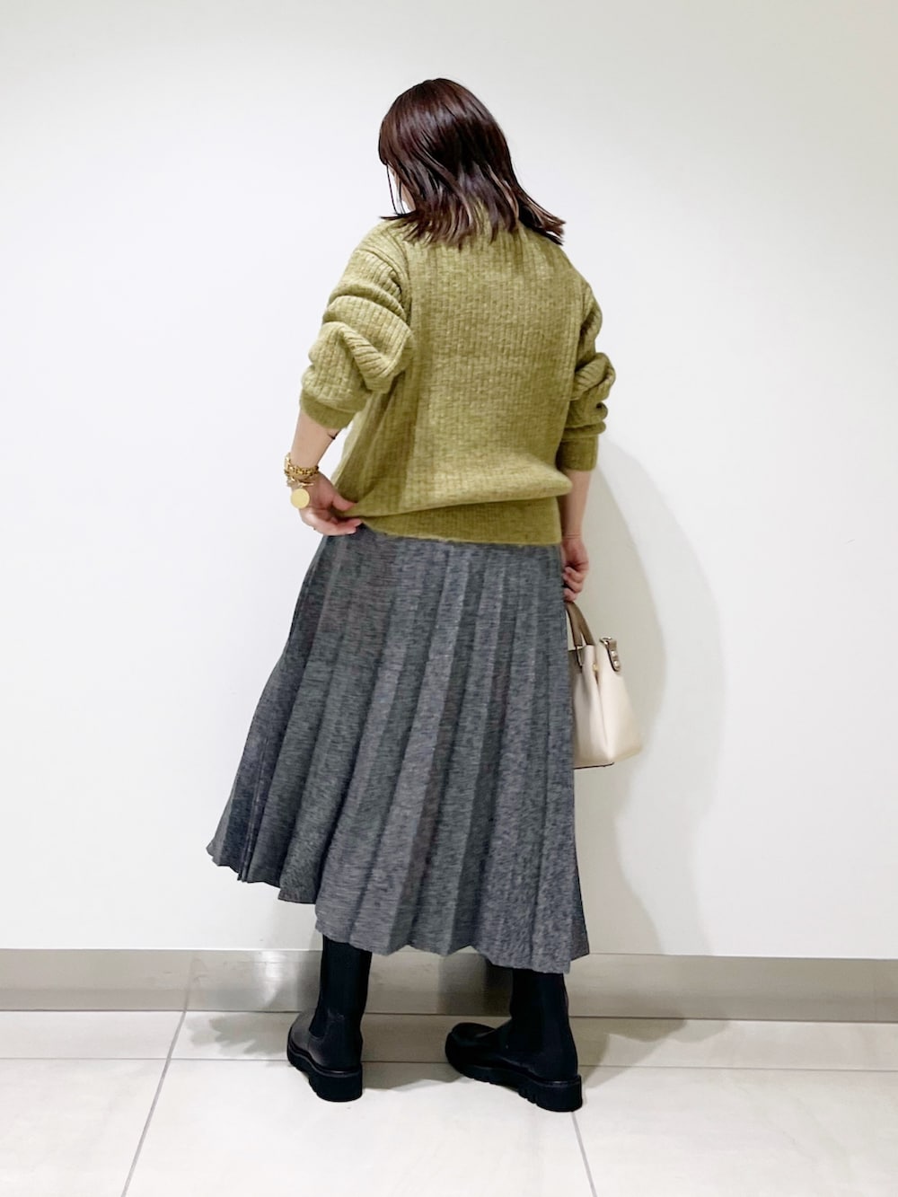 グリーン系のニット/セーター、ブルー系のスカート、ホワイト系のトートバッグを着用したレディースの冬コーディネートの6枚目の写真