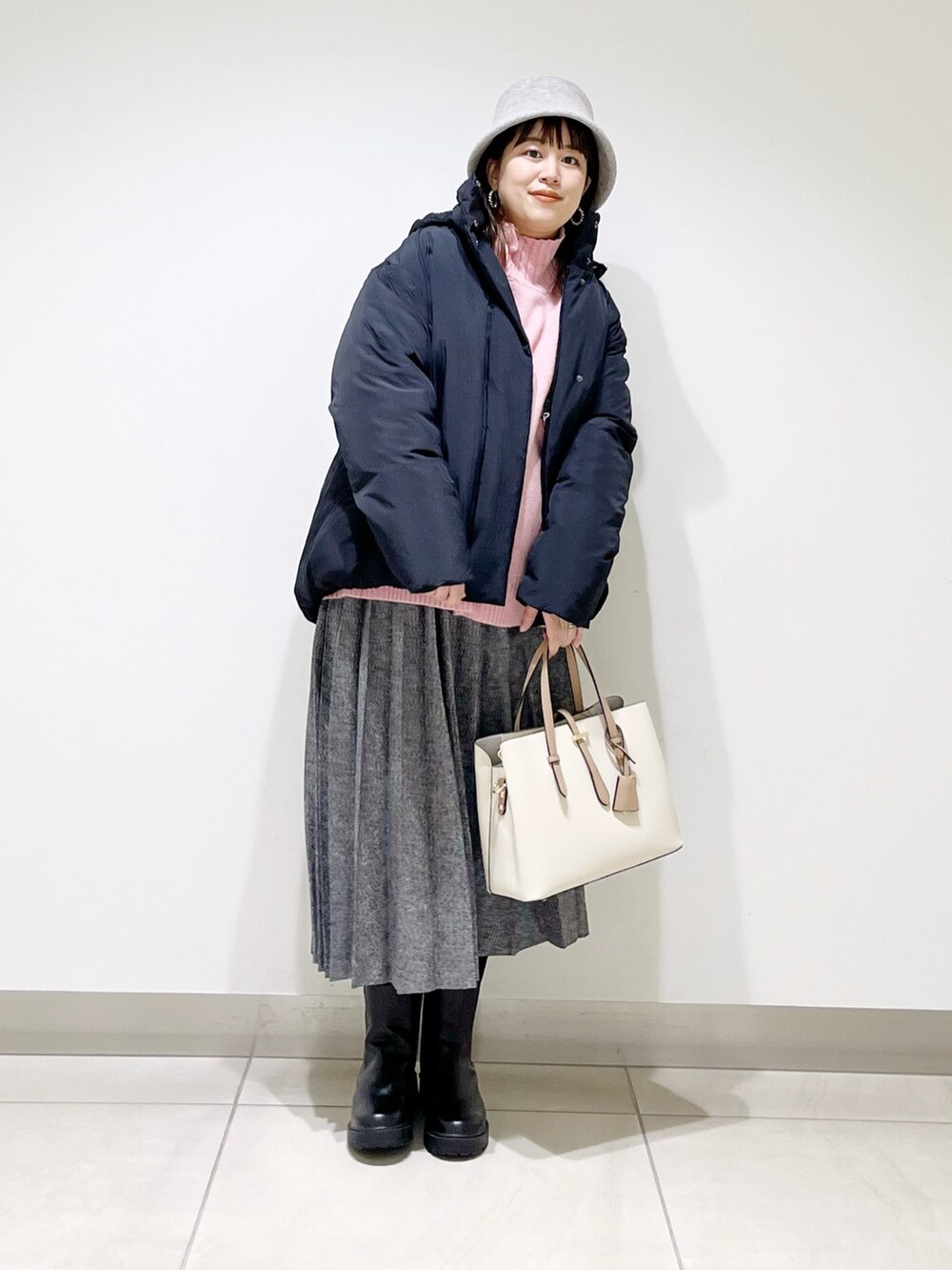 ブラック系のダウンジャケット/コート、ピンク系のニット/セーター、ブルー系のスカートを着用したレディースの冬コーディネートの7枚目の写真