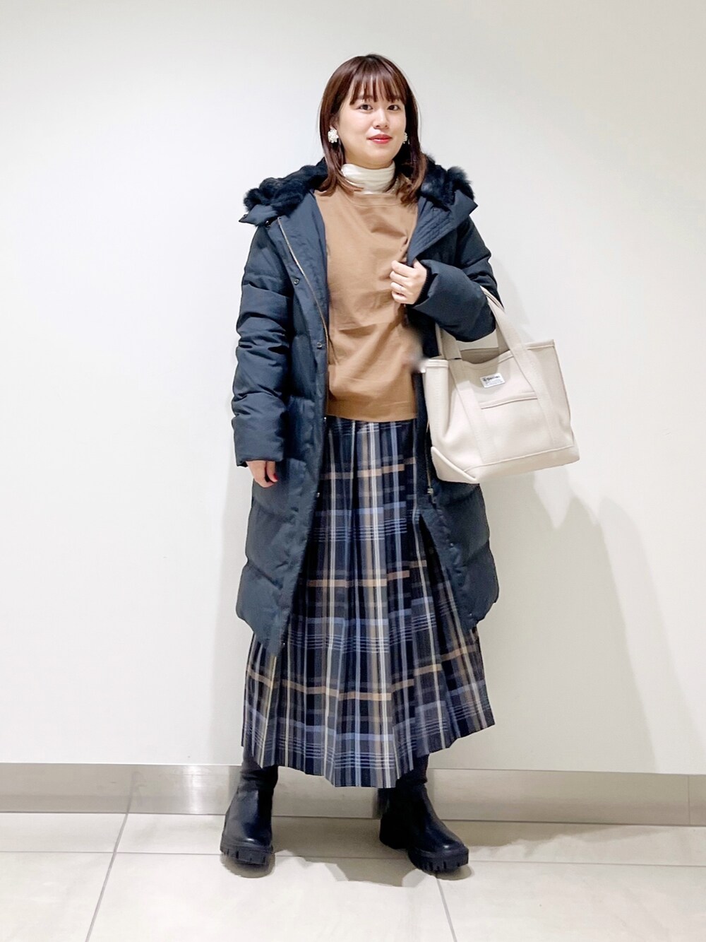 イエロー系のTシャツ/カットソー、ブラック系のダウンジャケット/コート、ブルー系のスカートを着用したレディースの秋コーディネートの7枚目の写真