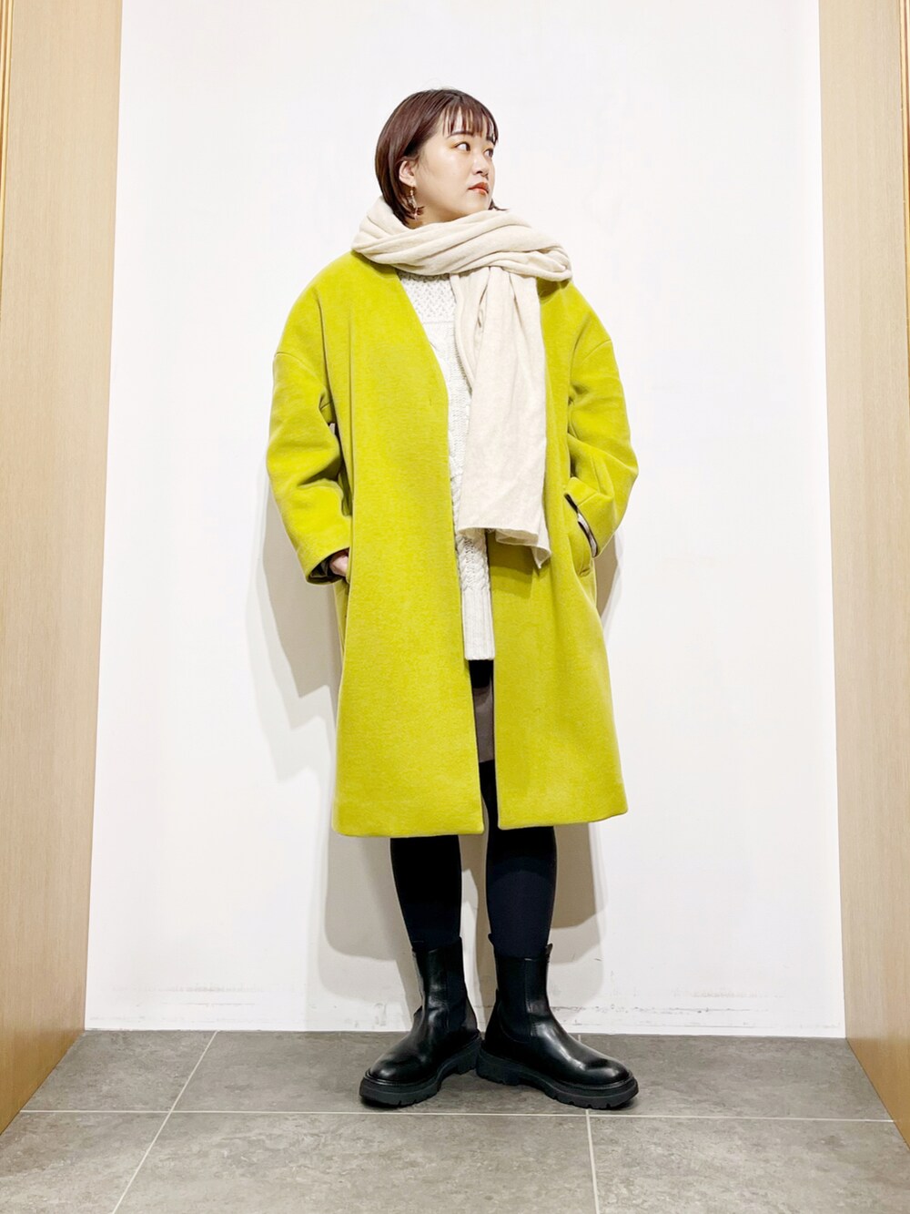 イエロー系のその他アウター、ホワイト系のニット/セーター、ブラック系のブーツを着用したレディースの冬コーディネートの5枚目の写真