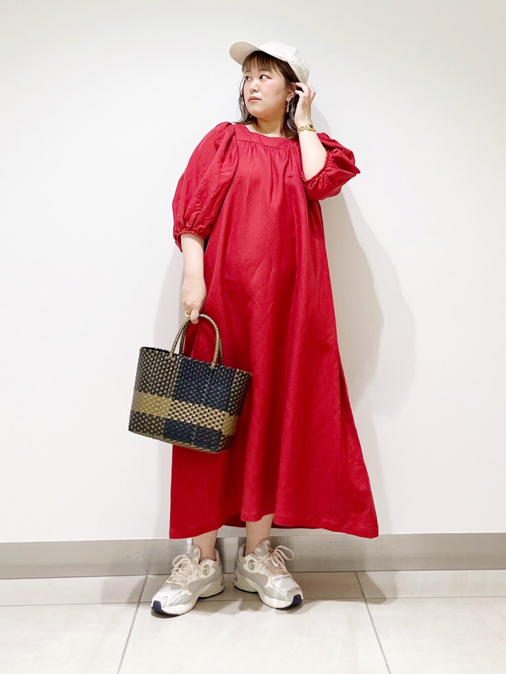 レッド系のワンピース、ホワイト系のスニーカー、ブラック系のトートバッグを着用したレディースの夏コーディネートの3枚目の写真