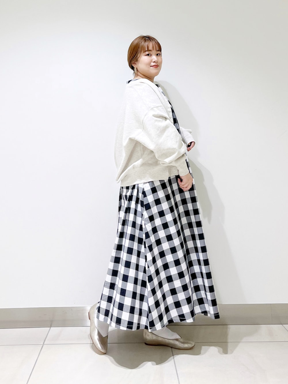 ブラック系のワンピース、グレー系のカーディガン/ボレロ、ゴールド系のパンプスを着用したレディースの春コーディネートの2枚目の写真