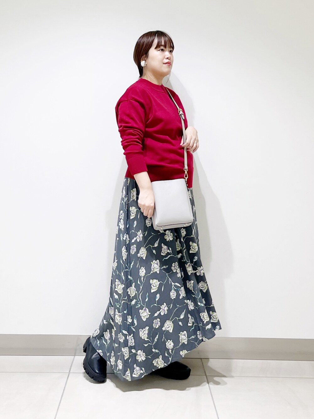 レッド系のトップス、グレー系のスカート、グレー系のショルダーバッグを着用したレディースの秋コーディネートの10枚目の写真