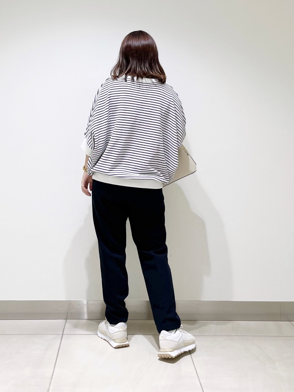 ホワイト系のTシャツ/カットソー、ブルー系のパンツ、ホワイト系のハンドバッグを着用したレディースの秋コーディネートの6枚目の写真