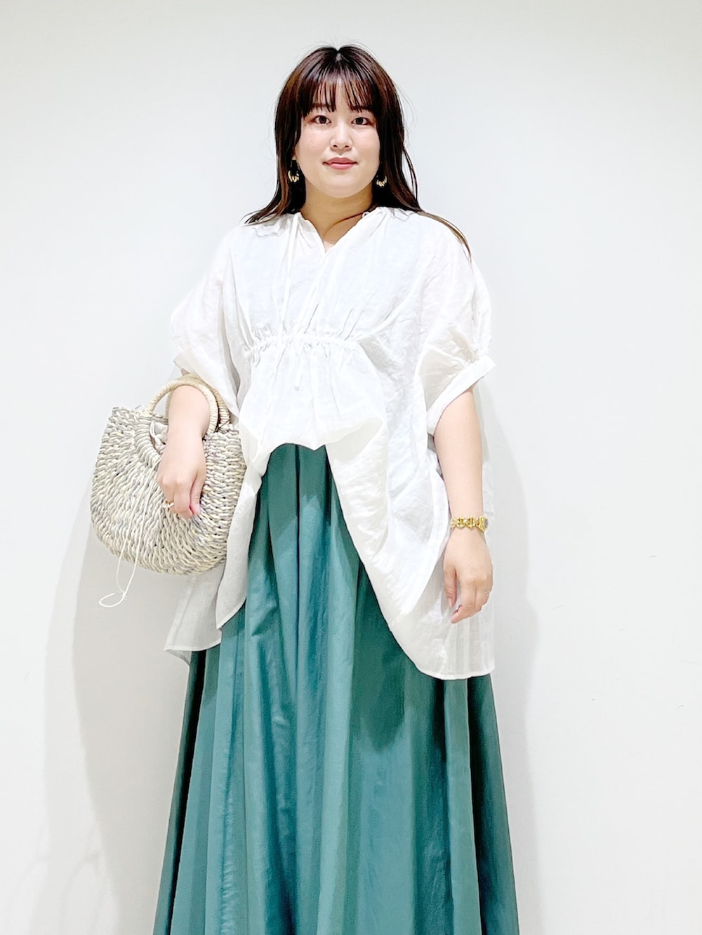 ホワイト系のシャツ/ブラウス、グリーン系のスカート、グレー系のかごバッグを着用したレディースの夏コーディネートの3枚目の写真