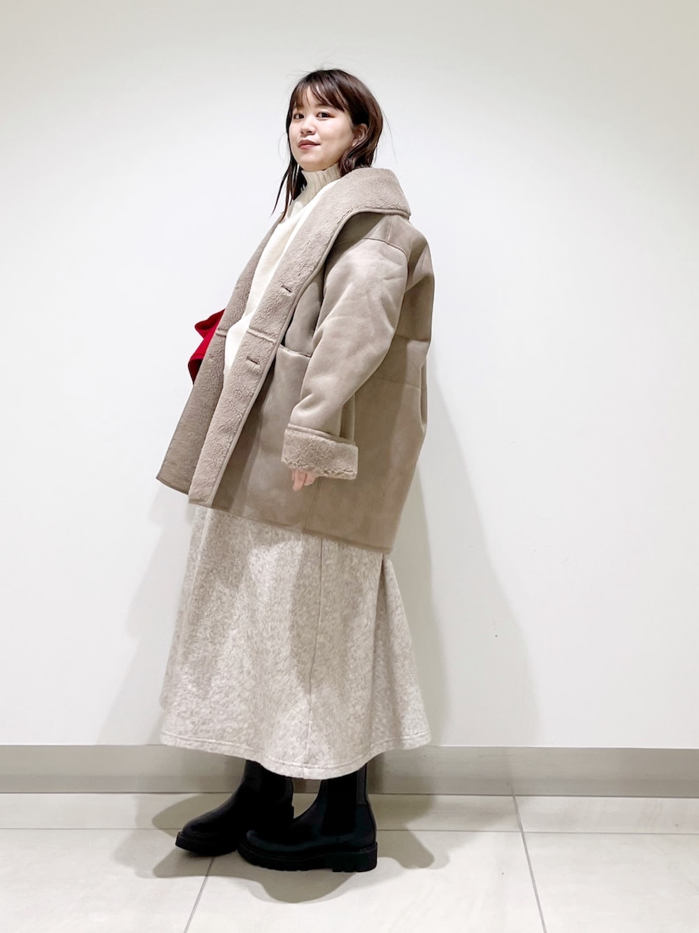 グレー系のムートンコート、ホワイト系のニット/セーター、ベージュ系のスカートを着用したレディースの冬コーディネートの5枚目の写真