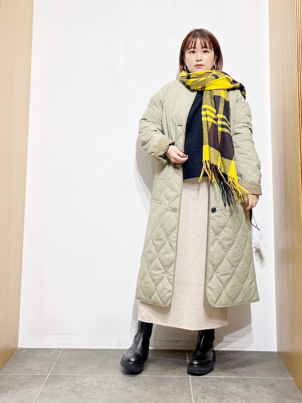 グリーン系のその他アウター、ブラック系のブーツ、ベージュ系のスカートを着用したレディースの冬コーディネートの2枚目の写真