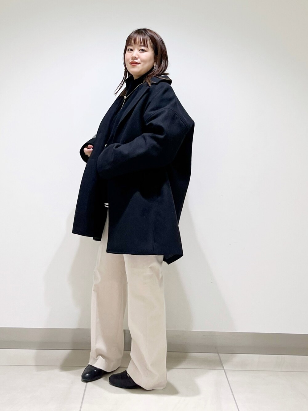 ブルー系のピーコート、ブラック系のニット/セーター、ホワイト系のTシャツ/カットソーを着用したレディースの冬コーディネートの5枚目の写真