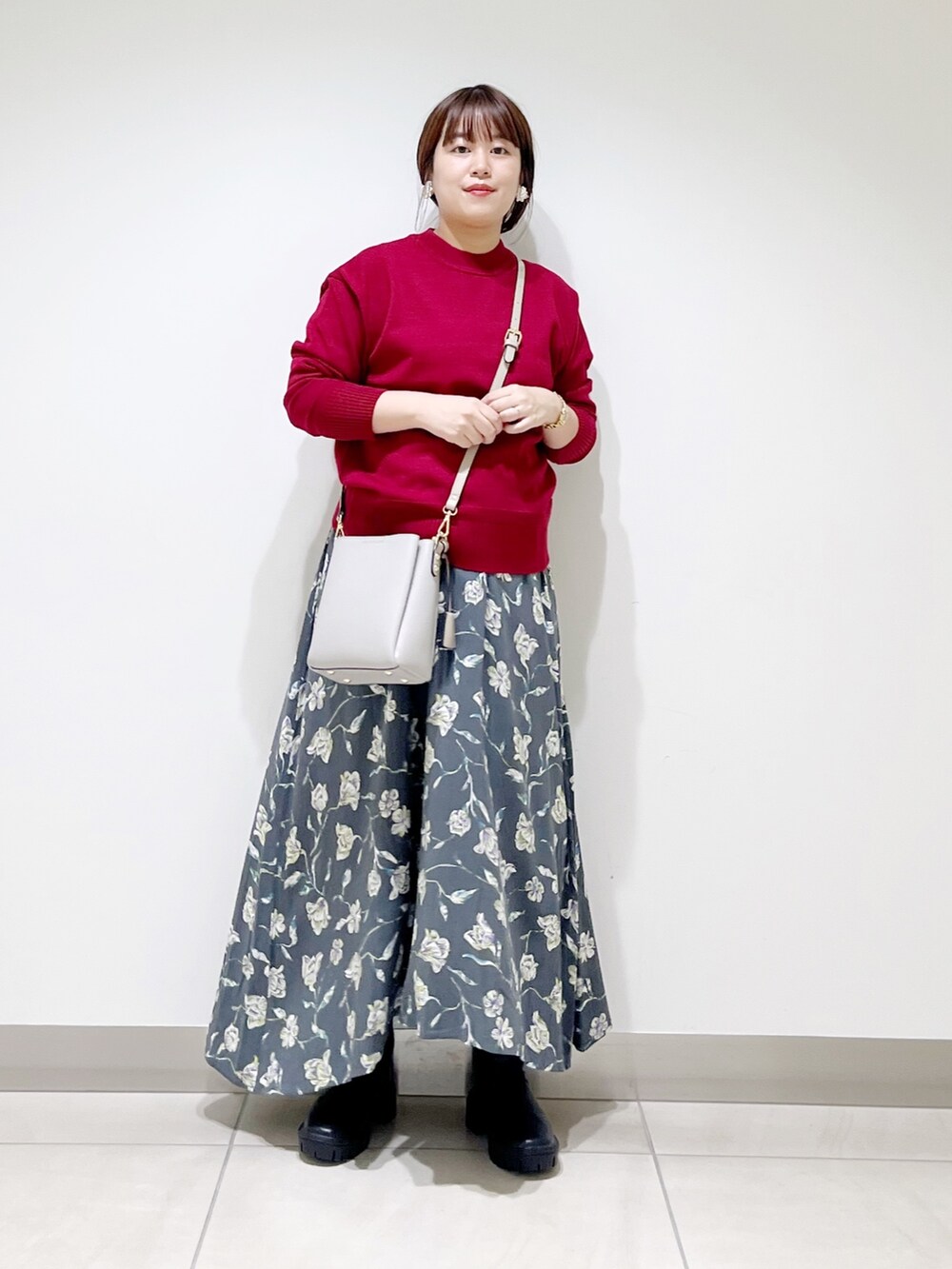レッド系のトップス、グレー系のスカート、グレー系のショルダーバッグを着用したレディースの秋コーディネートの5枚目の写真