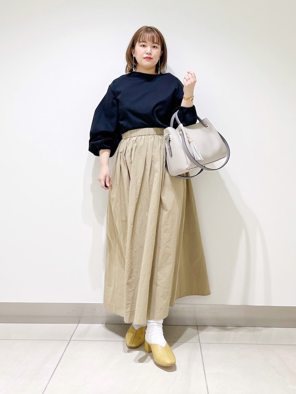 ブラック系のTシャツ/カットソー、ベージュ系のスカート、グレー系のトートバッグを着用したレディースの春コーディネートの5枚目の写真