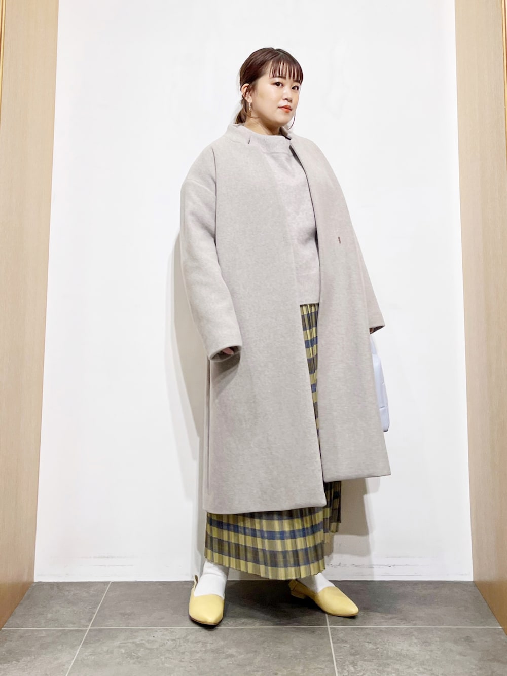 ベージュ系のニット/セーター、グレー系のその他アウター、イエロー系のスカートを着用したレディースの冬コーディネートの2枚目の写真