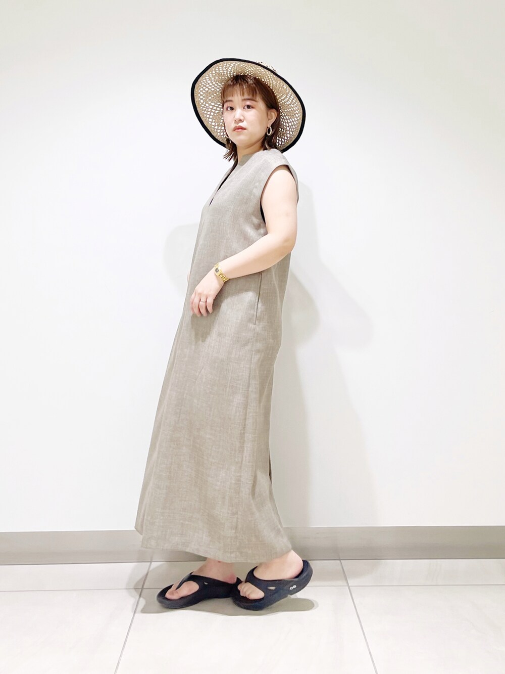グレー系のワンピース、ブラック系のサンダル、ブラック系のハットを着用したレディースの春コーディネートの5枚目の写真