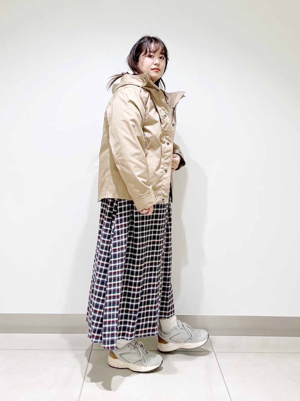 ベージュ系のマウンテンパーカー、ブラウン系のワンピース、グレー系のスニーカーを着用したレディースの春コーディネートの5枚目の写真