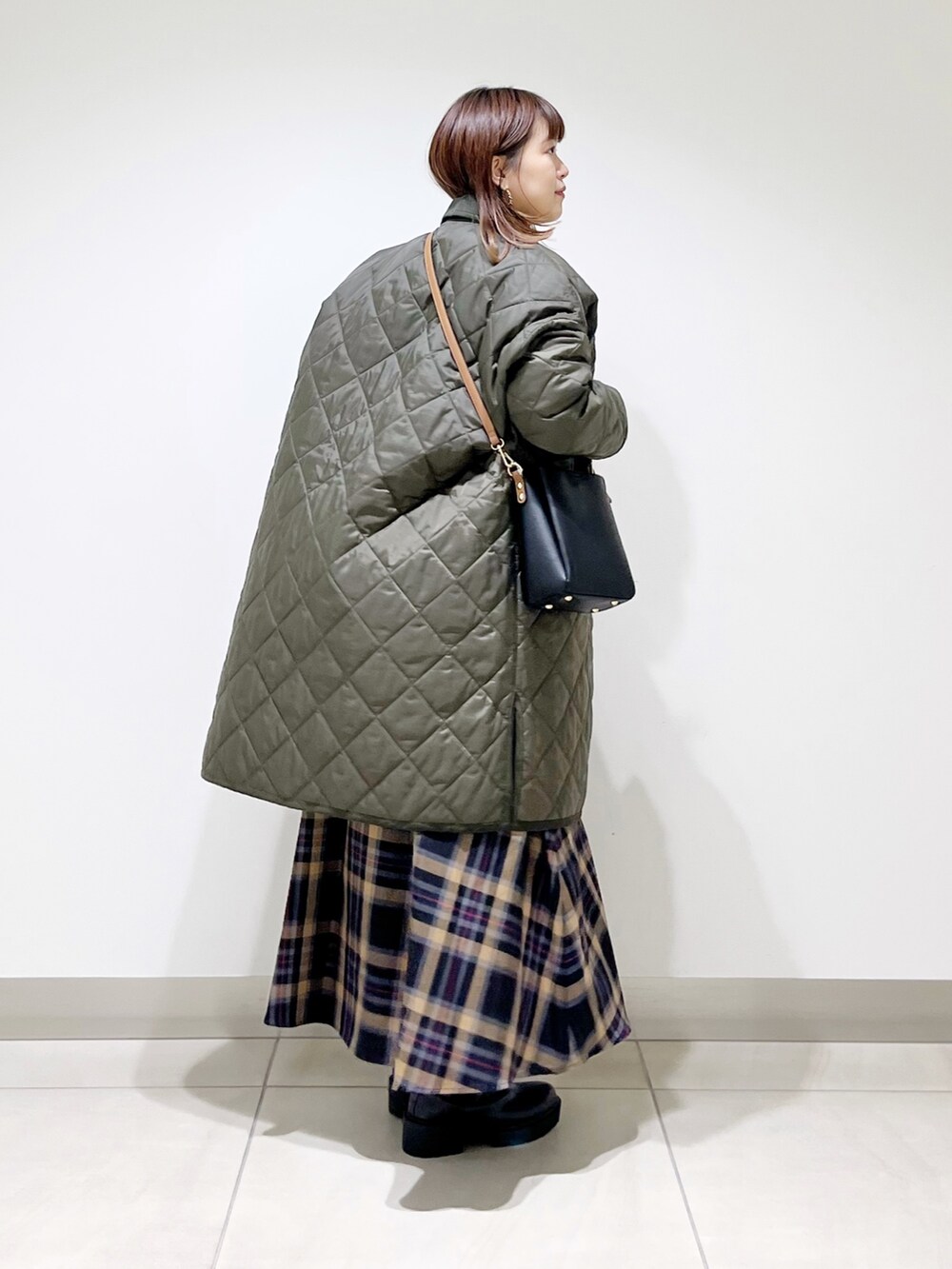 グリーン系のダウンジャケット/コート、ホワイト系のトップス、ブラウン系のスカートを着用したレディースの秋コーディネートの8枚目の写真