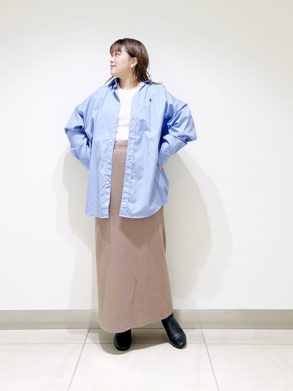 ブルー系のシャツ/ブラウス、ベージュ系のスカート、ブラック系のブーツを着用したレディースの秋コーディネートの5枚目の写真