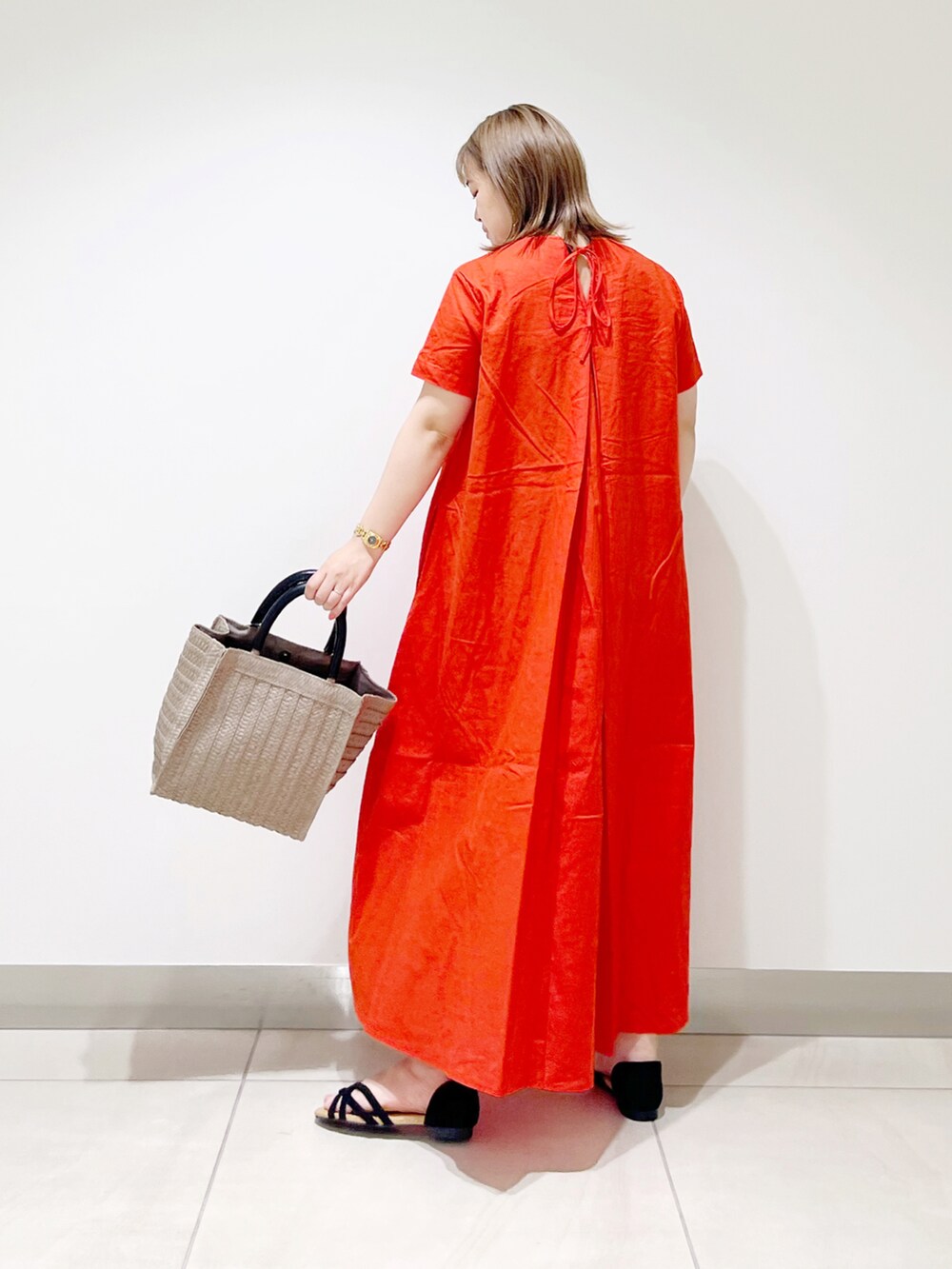 レッド系のワンピース、ベージュ系のトートバッグ、ブラック系のサンダルを着用したレディースの夏コーディネートの2枚目の写真