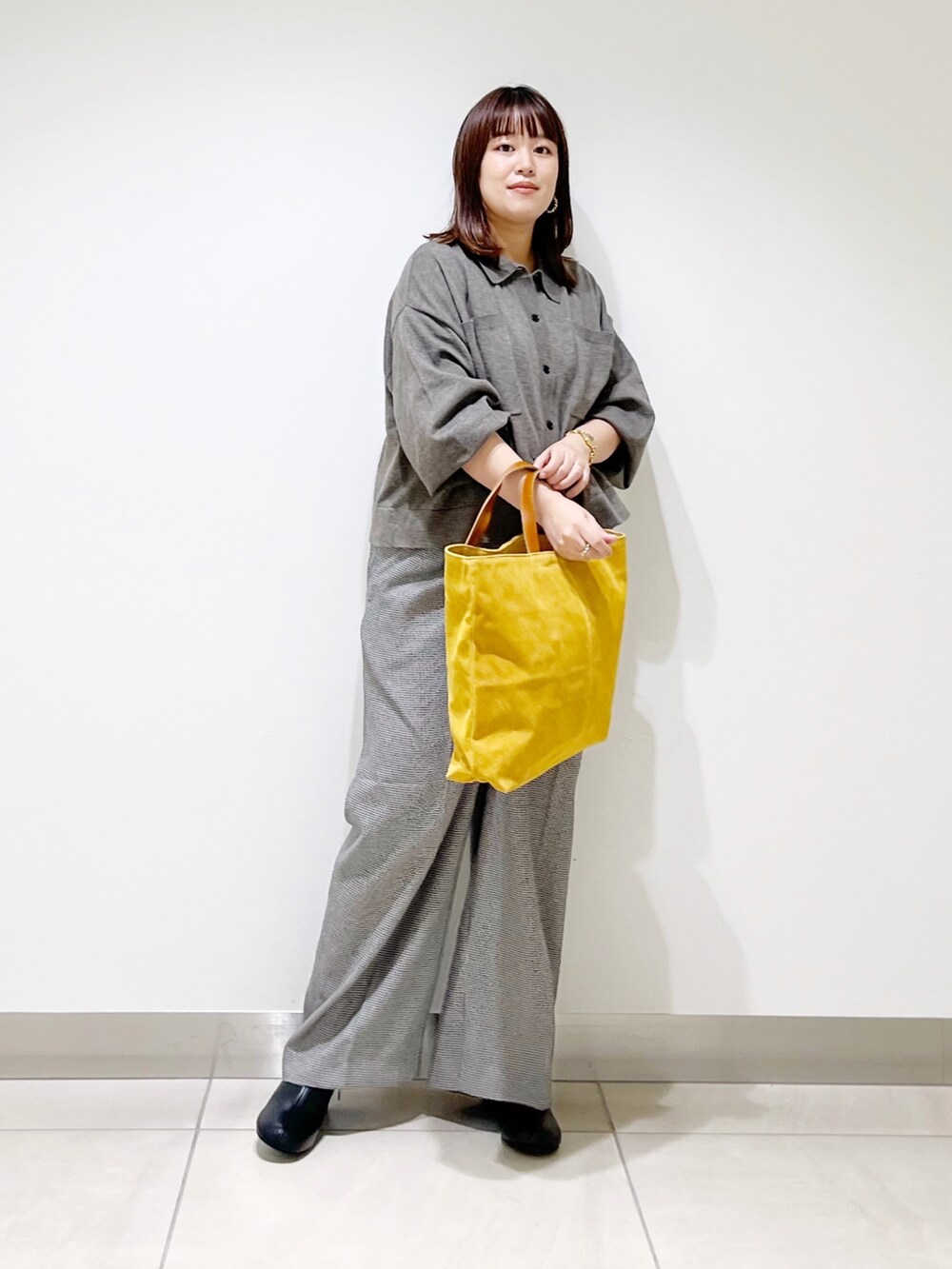 グレー系のニット/セーター、ベージュ系のパンツ、イエロー系のトートバッグを着用したレディースの秋コーディネートの2枚目の写真