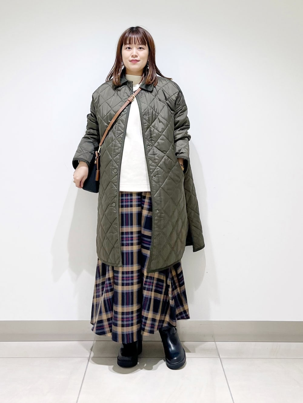 グリーン系のダウンジャケット/コート、ホワイト系のトップス、ブラウン系のスカートを着用したレディースの秋コーディネートの3枚目の写真