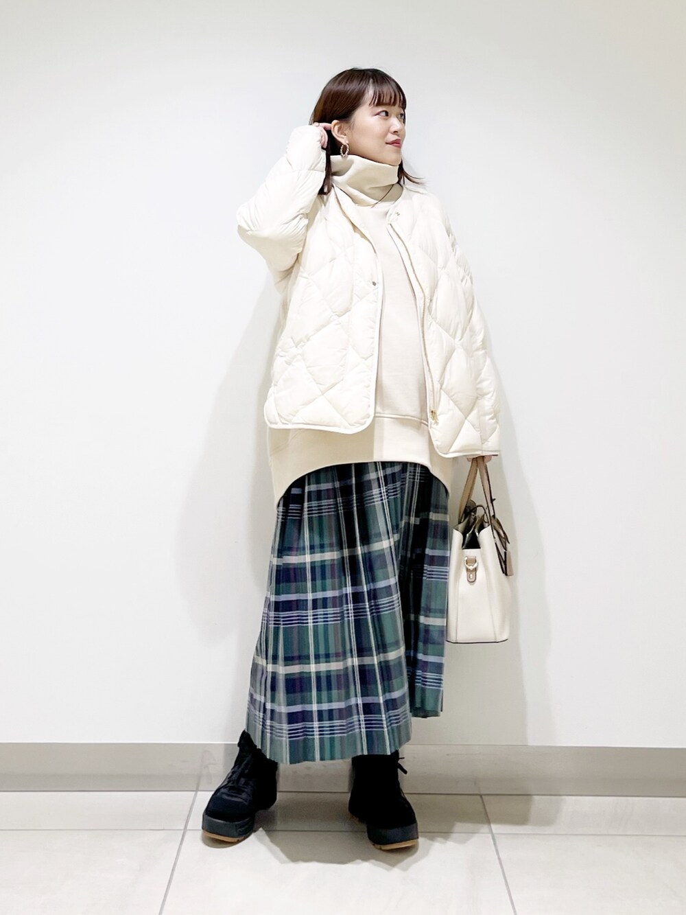 ベージュ系のスウェット、ホワイト系のダウンジャケット/コート、グリーン系のスカートを着用したレディースの秋コーディネートの6枚目の写真