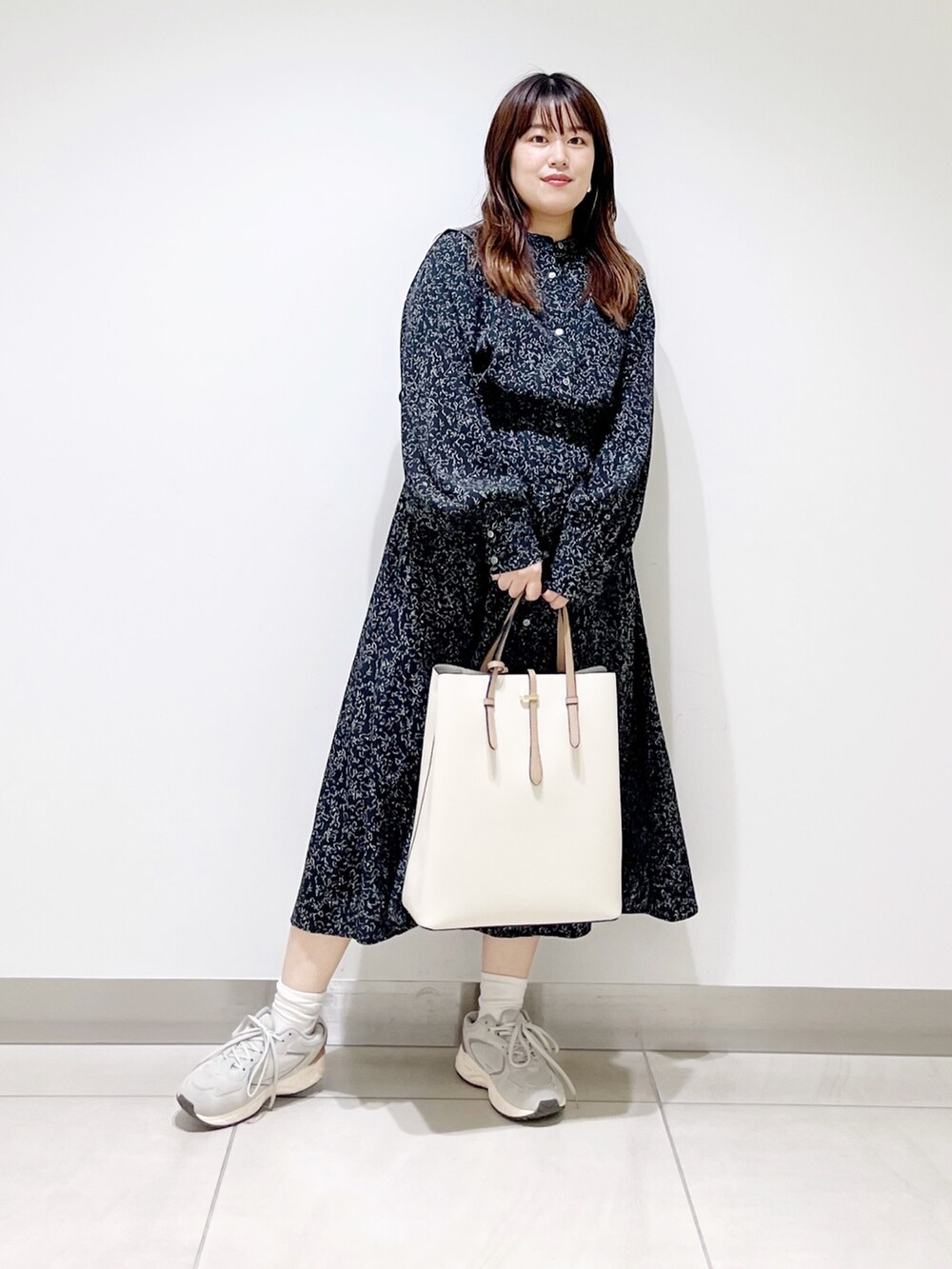 ブラック系のワンピース、ホワイト系のトートバッグ、グレー系のスニーカーを着用したレディースの夏コーディネートの6枚目の写真