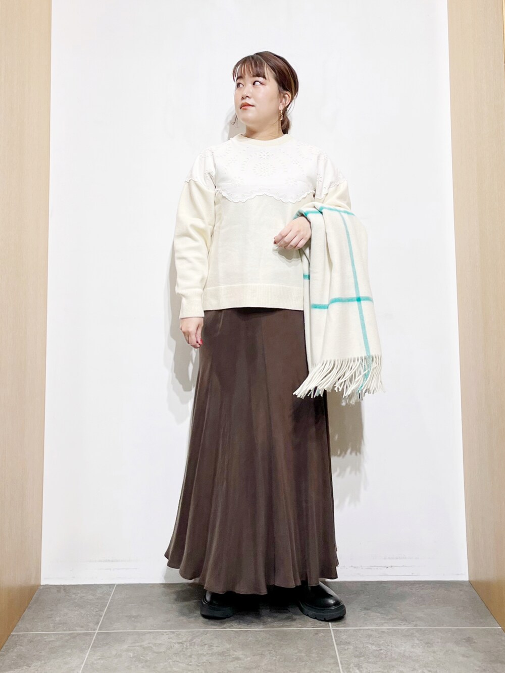 ブラウン系のスカート、ホワイト系のニット/セーター、ブラック系のブーツを着用したレディースの冬コーディネートの5枚目の写真