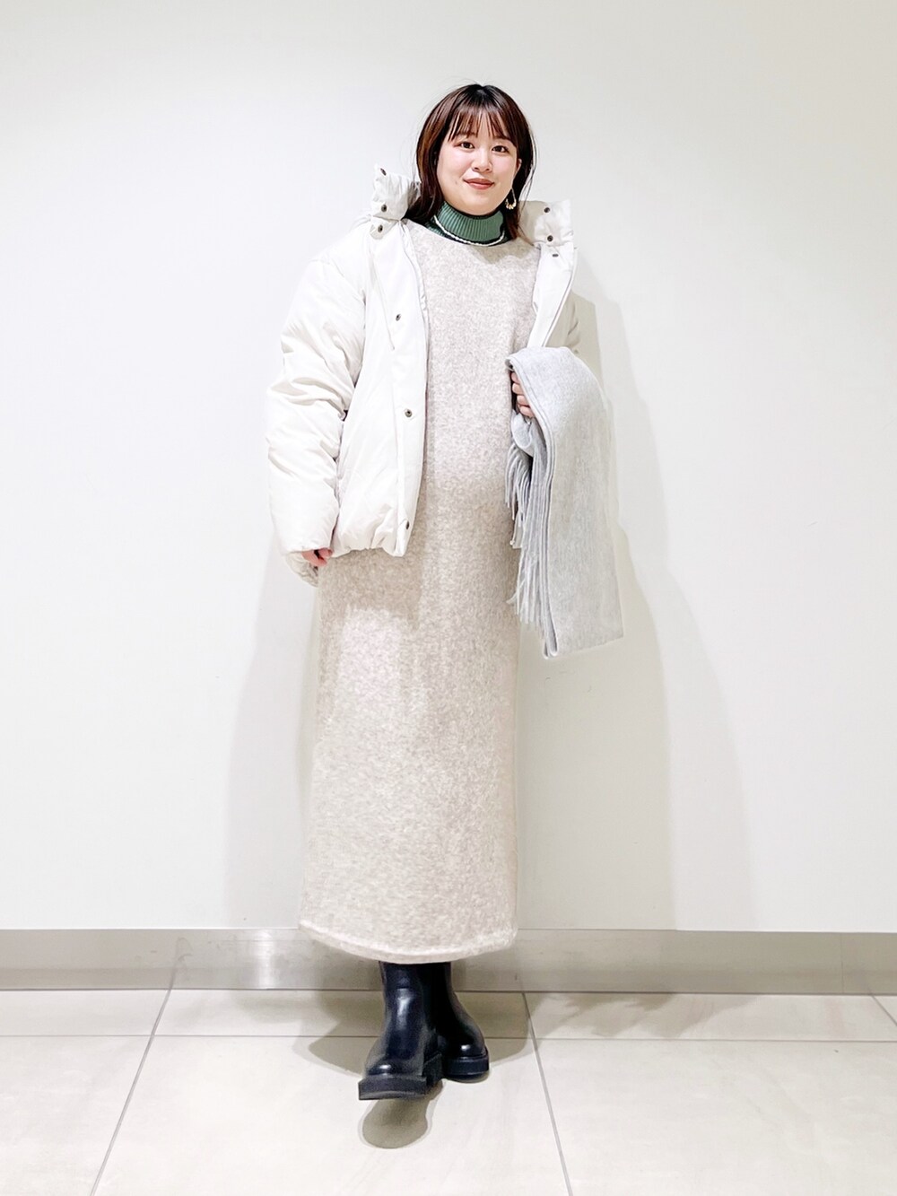 ホワイト系のダウンジャケット/コート、ベージュ系のワンピース、グリーン系のニット/セーターを着用したレディースの冬コーディネートの5枚目の写真