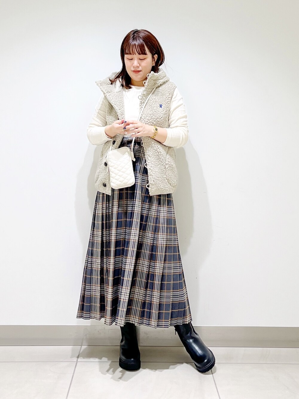 ホワイト系のトップス、グレー系のスカート、ブラック系のブーツを着用したレディースの秋コーディネートの10枚目の写真