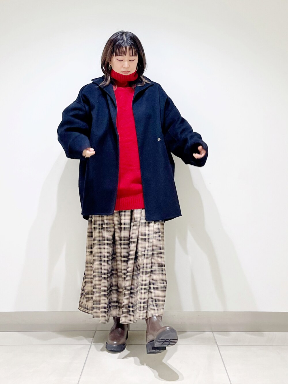 レッド系のニット/セーター、ブラック系のその他アウター、ベージュ系のスカートを着用したレディースの冬コーディネートの4枚目の写真