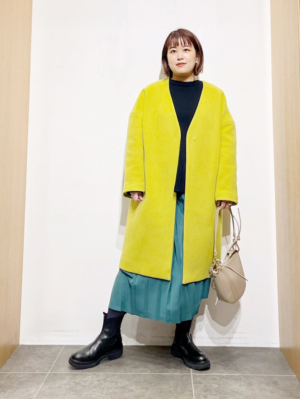 ブラック系のニット/セーター、イエロー系のその他アウター、グリーン系のスカートを着用したレディースの冬コーディネートの4枚目の写真