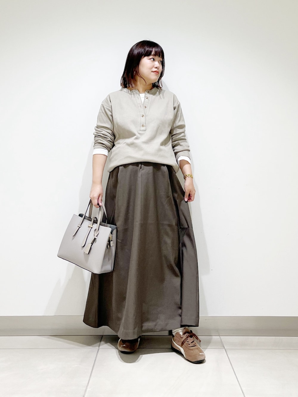 ベージュ系のTシャツ/カットソー、ブラウン系のスカート、グレー系のトートバッグを着用したレディースの秋コーディネートの2枚目の写真