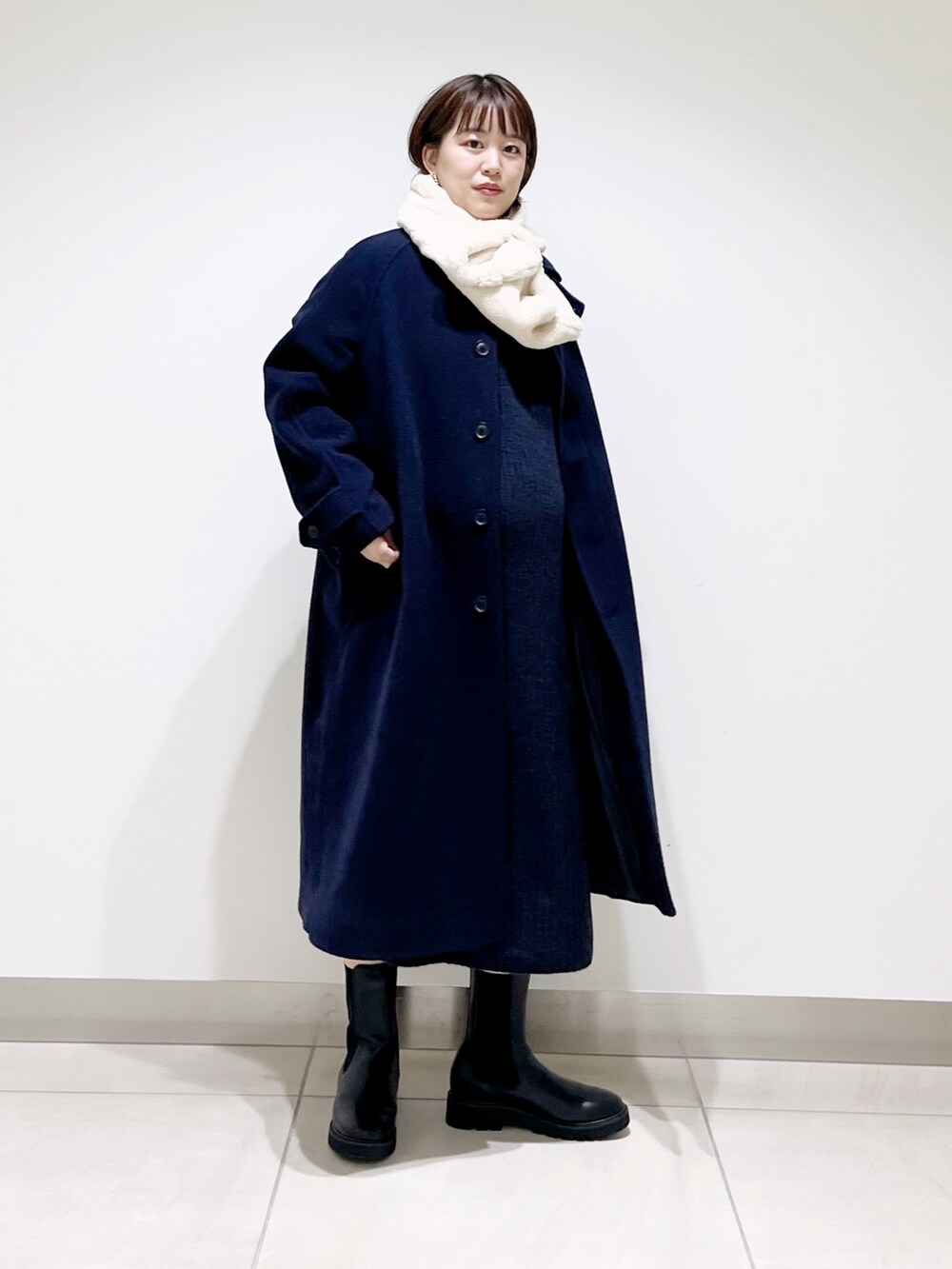ブルー系のステンカラーコート、ブルー系のワンピース、ブラック系のブーツを着用したレディースの冬コーディネートの6枚目の写真