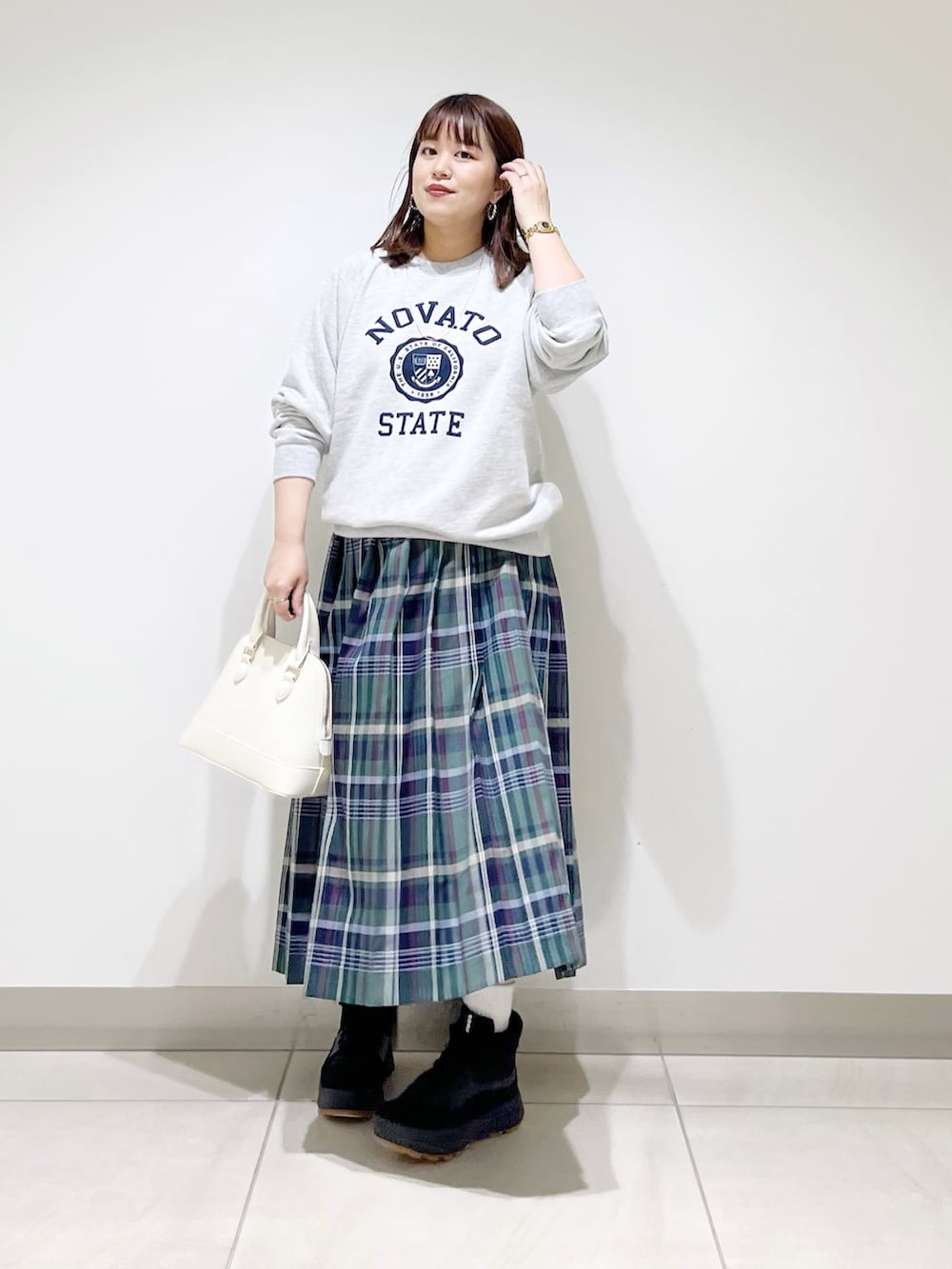 グリーン系のスカート、グレー系のスウェット、ホワイト系のショルダーバッグを着用したレディースの冬コーディネートの2枚目の写真