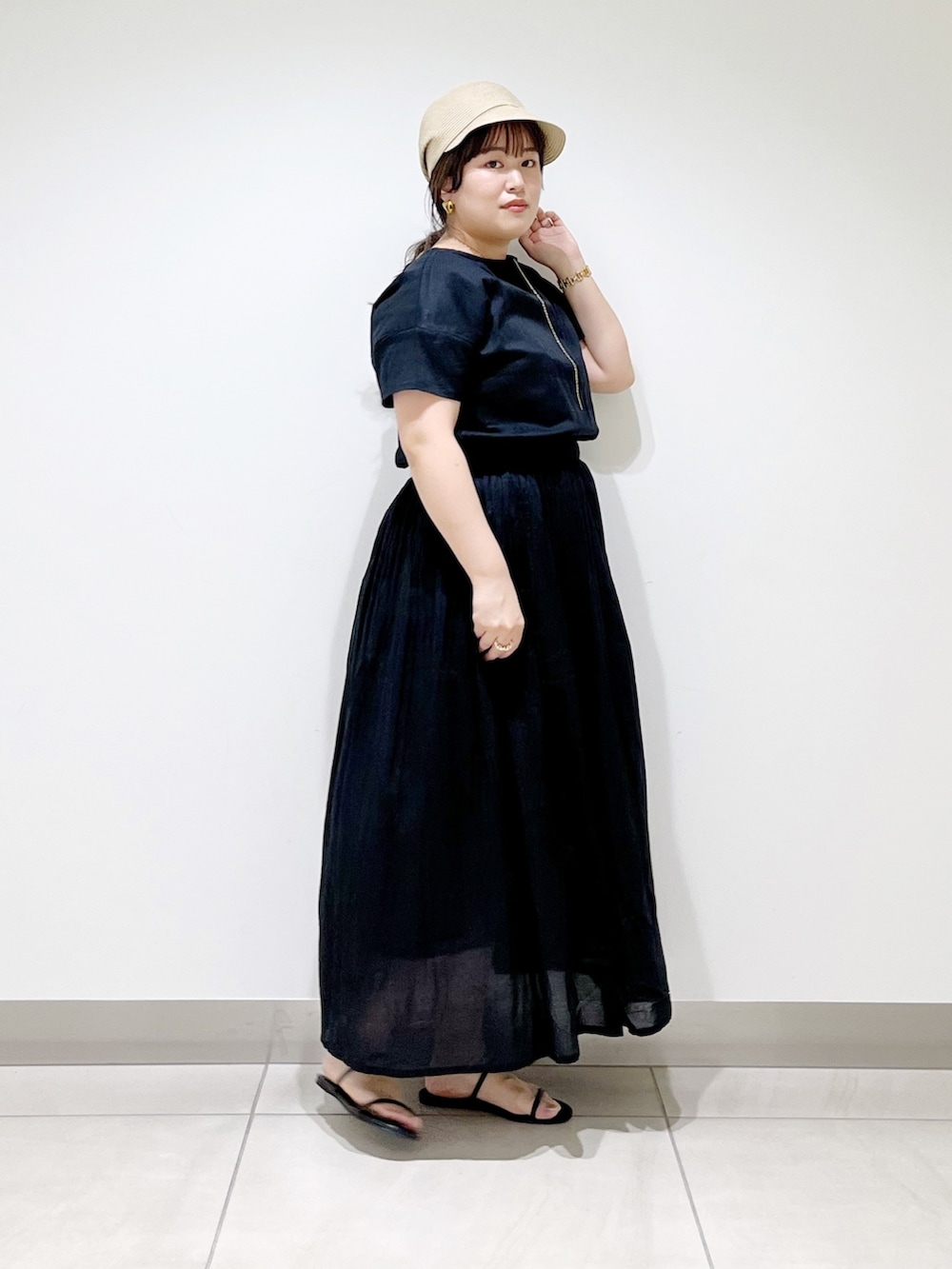 ブラック系のワンピース、ブラック系のサンダル、ベージュ系のキャスケットを着用したレディースの夏コーディネートの2枚目の写真