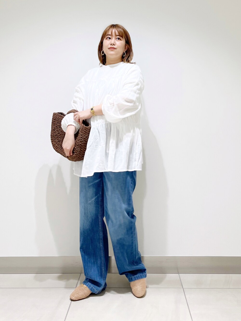 ホワイト系のシャツ/ブラウス、ブラウン系のハンドバッグ、ブルー系のデニムパンツを着用したレディースの春コーディネートの3枚目の写真