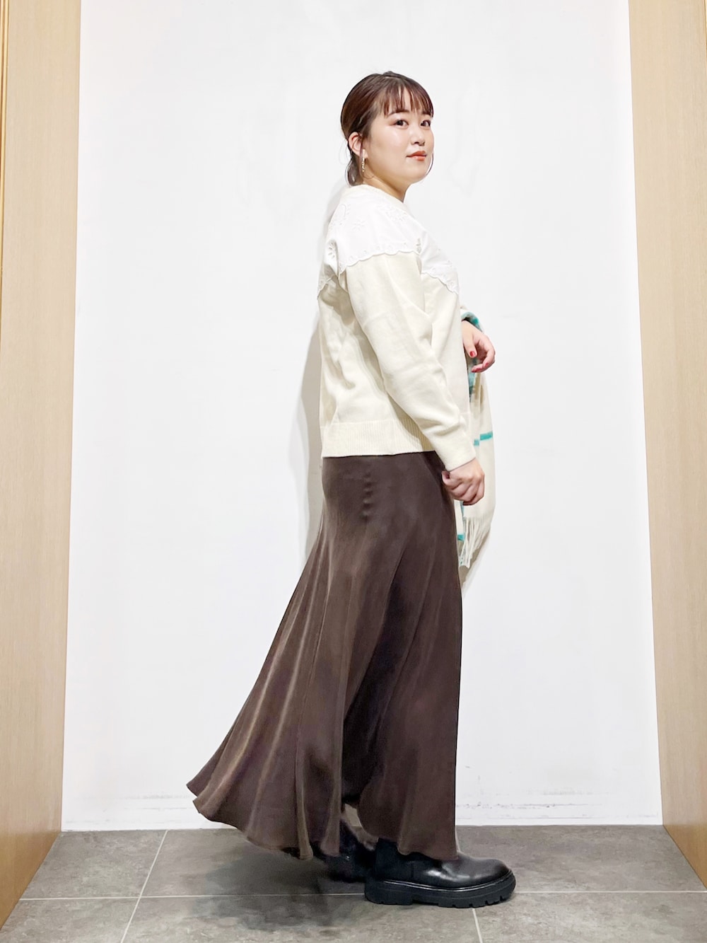 ブラウン系のスカート、ホワイト系のニット/セーター、ブラック系のブーツを着用したレディースの冬コーディネートの2枚目の写真