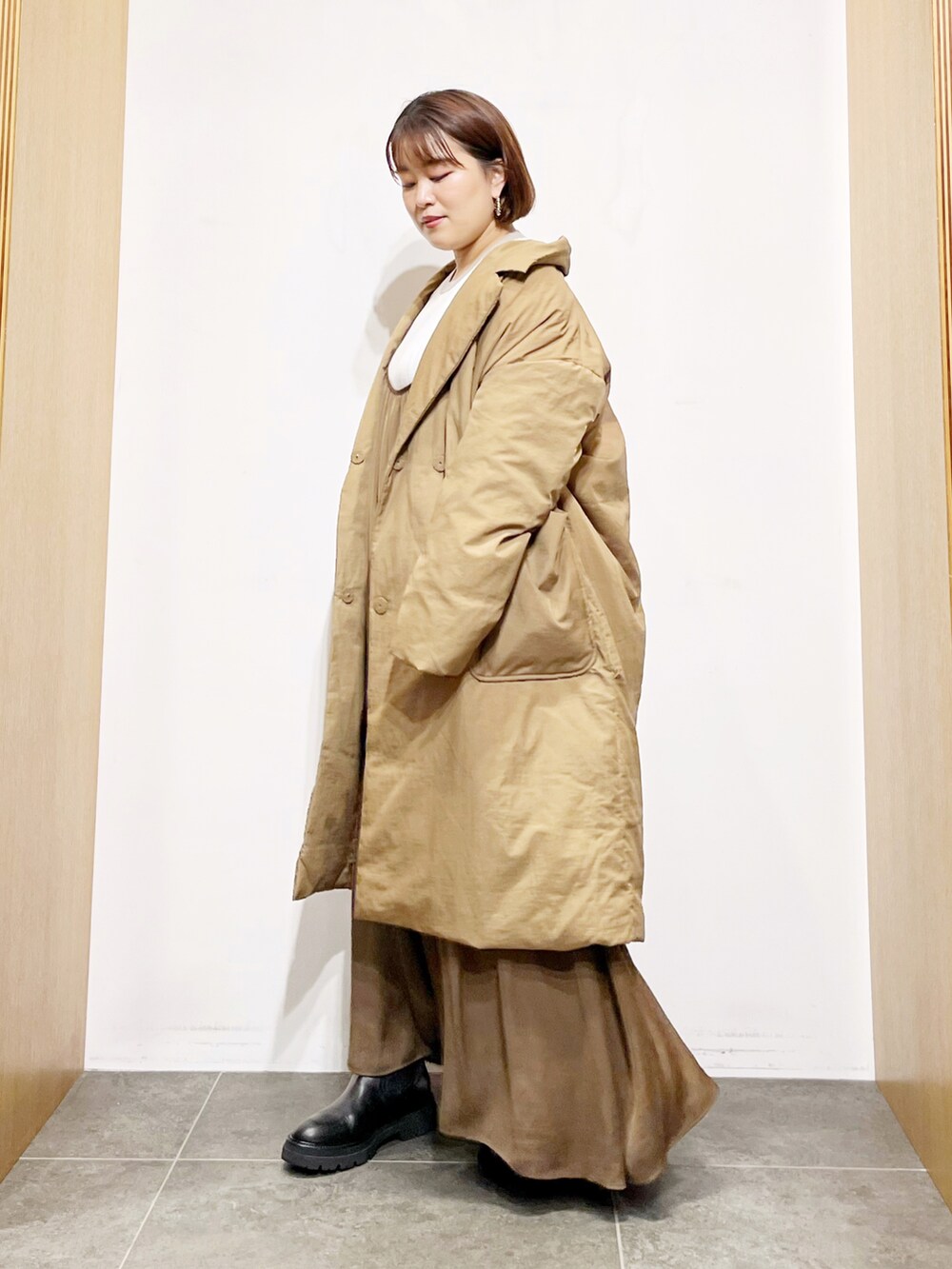 ベージュ系のダウンジャケット/コート、ブラウン系のワンピース、ホワイト系のニット/セーターを着用したレディースの秋コーディネートの5枚目の写真